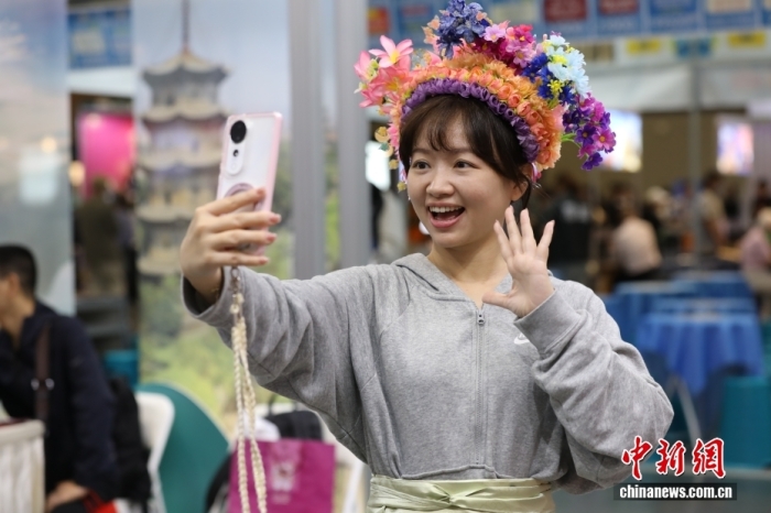 2025年11月21日至24日，以“来福建 福气多 一路山海一路歌”为主题的福建旅游主题推介暨精彩福建图片展亮相台南旅展。图为台湾青年在展区体验簪花。中新社记者 朱贺 摄